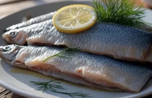 три селёдки с лимнчиком и зеленью на тарелке