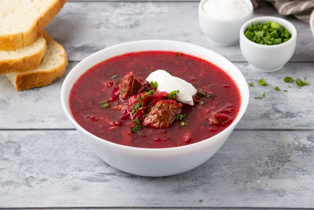 Красный суп в тарелки с мясом и сметаной